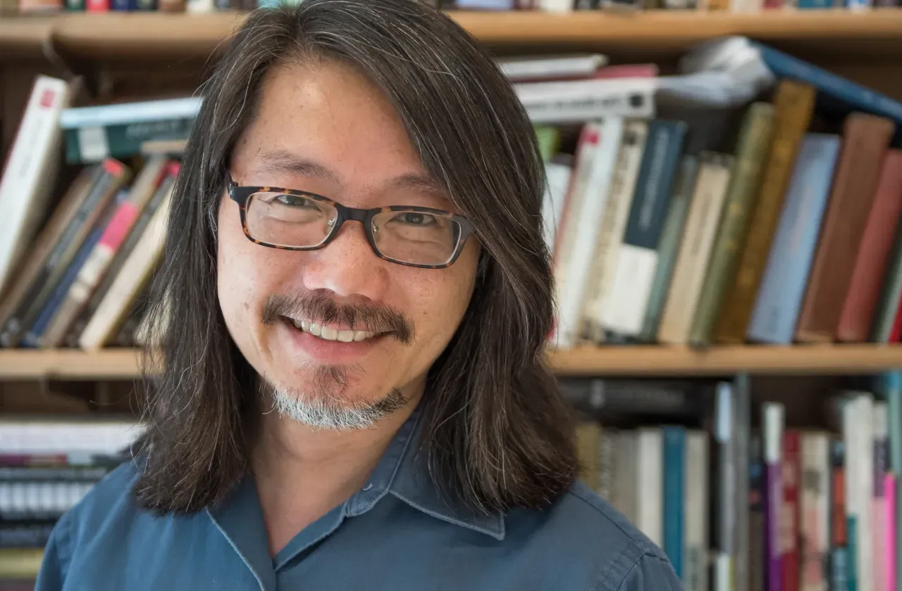 Floyd Cheung in front of a bookshelf.