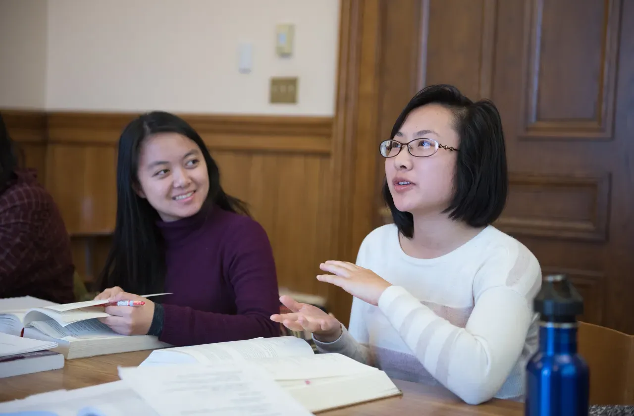 Two students having a discussion in a classroom.