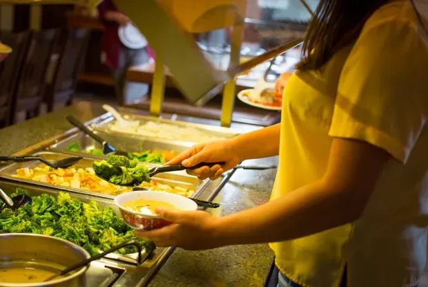 Closeup of a student making selections from a salad bar